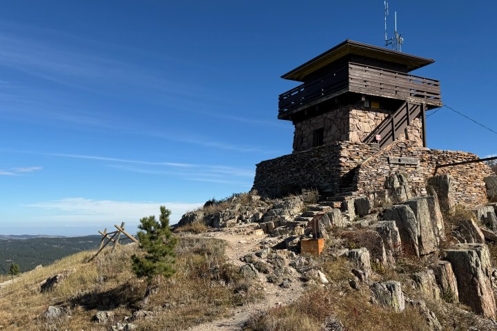 Stone observation tower on a hill under clear blue sky.